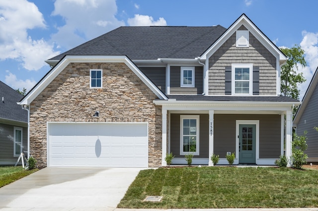 view of front of property featuring a front yard, covered porch, and a garage