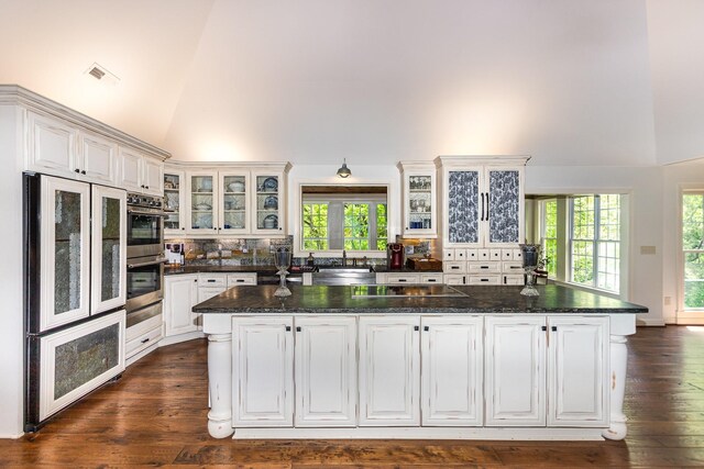 884 Pinnacle Hill Rd, Kingston Springs, TN 37082 - kitchen featuring high vaulted ceiling, stainless steel double oven, dark wood finished floors, decorative backsplash, and glass insert cabinets