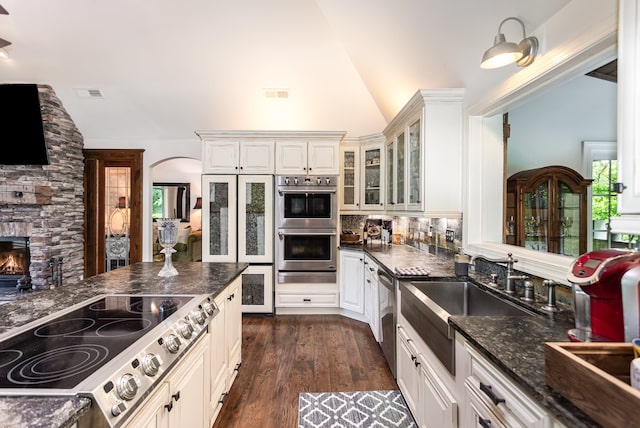 kitchen featuring stainless steel appliances, dark hardwood / wood-style floors, white cabinets, and vaulted ceiling