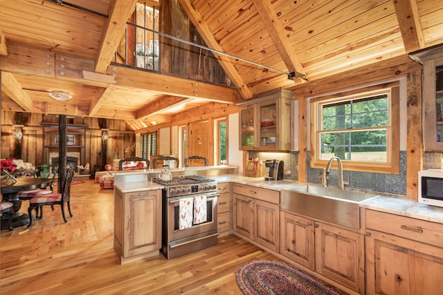 kitchen with kitchen peninsula, high end stainless steel range oven, sink, and light wood-type flooring