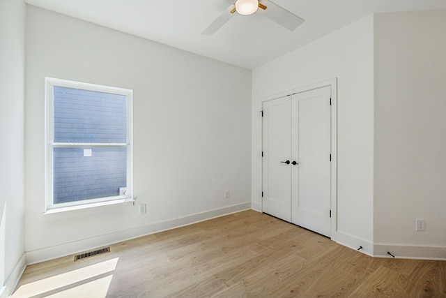 unfurnished bedroom with light wood-type flooring, ceiling fan, and a closet