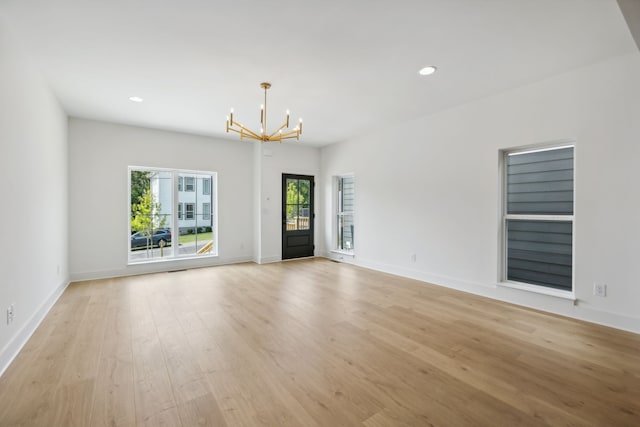 spare room with an inviting chandelier and light wood-type flooring