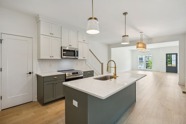 kitchen featuring stainless steel appliances, white cabinetry, sink, and pendant lighting