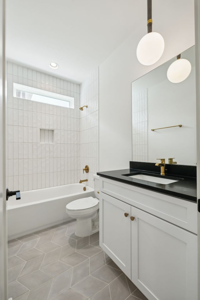 full bathroom featuring toilet, vanity, tiled shower / bath combo, and tile patterned floors