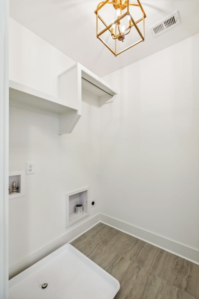 laundry area featuring wood-type flooring, hookup for a washing machine, hookup for an electric dryer, and an inviting chandelier