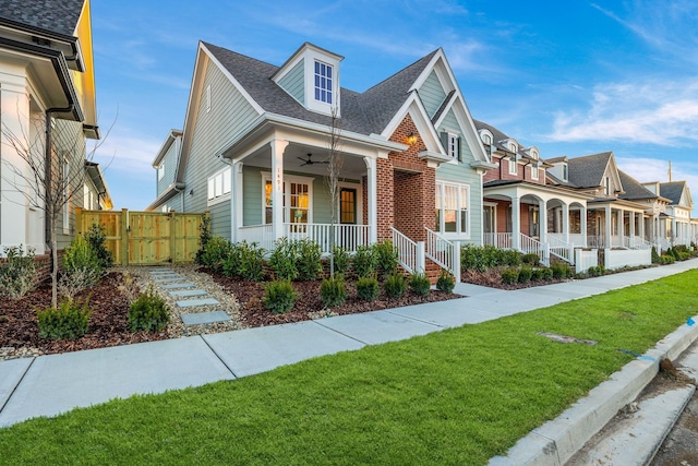 view of front of home featuring ceiling fan, a front yard, and covered porch