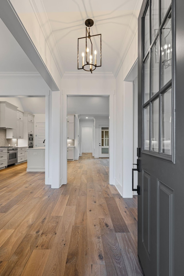 foyer entrance featuring ornamental molding, a chandelier, and light hardwood / wood-style floors