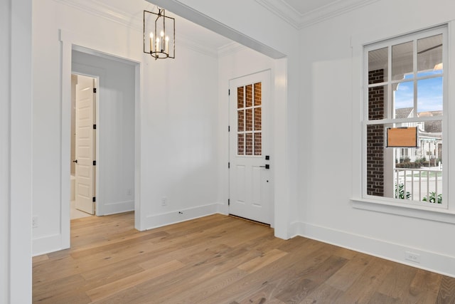 entryway with a notable chandelier, ornamental molding, and light hardwood / wood-style floors