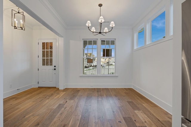 unfurnished dining area with hardwood / wood-style floors, ornamental molding, and a chandelier