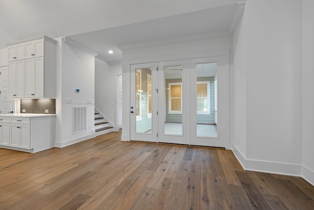 spare room with ornamental molding and light wood-type flooring