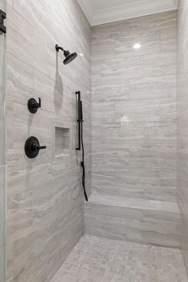 bathroom featuring ornamental molding and tiled shower