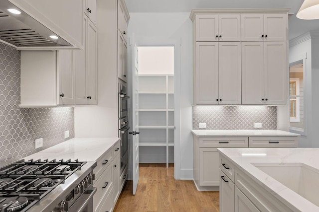 kitchen featuring light hardwood / wood-style flooring, light stone counters, stainless steel range, custom range hood, and white cabinets