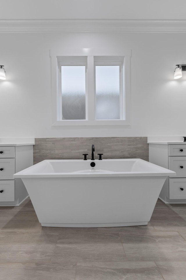 bathroom featuring crown molding, tile walls, vanity, and a bathtub