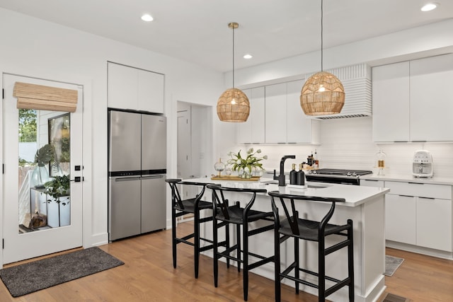 kitchen featuring appliances with stainless steel finishes, an island with sink, and white cabinets