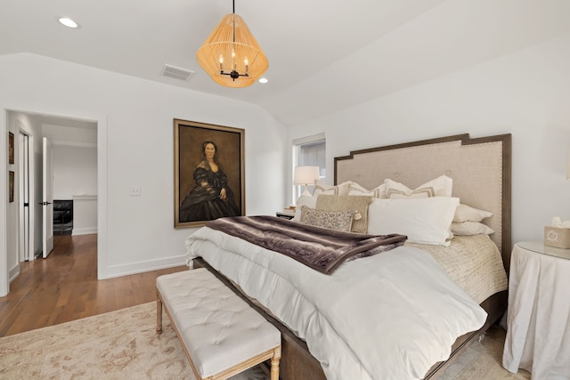 bedroom with hardwood / wood-style floors, a notable chandelier, and vaulted ceiling