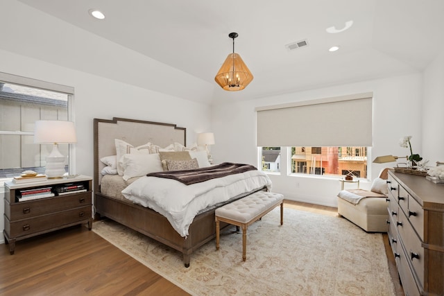 bedroom with lofted ceiling, an inviting chandelier, and light hardwood / wood-style floors