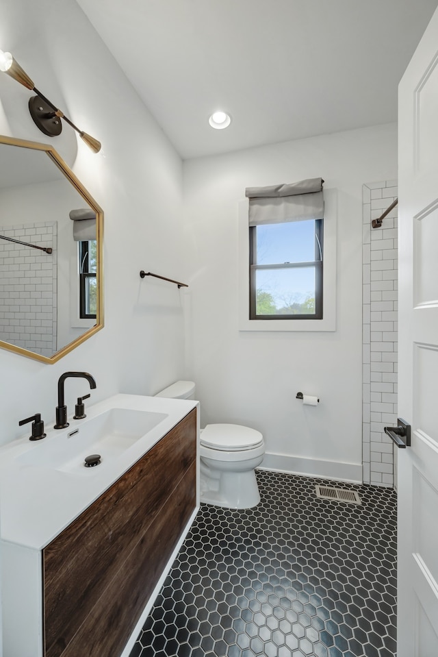 bathroom featuring vanity, tile patterned flooring, toilet, and a tile shower