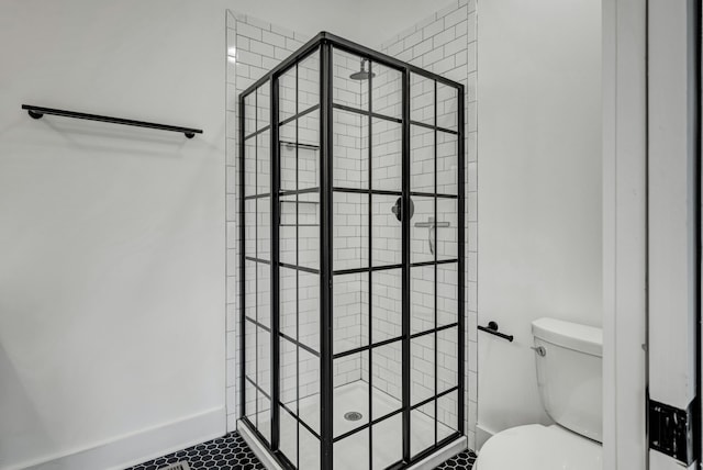 bathroom with toilet, tile patterned floors, and tiled shower