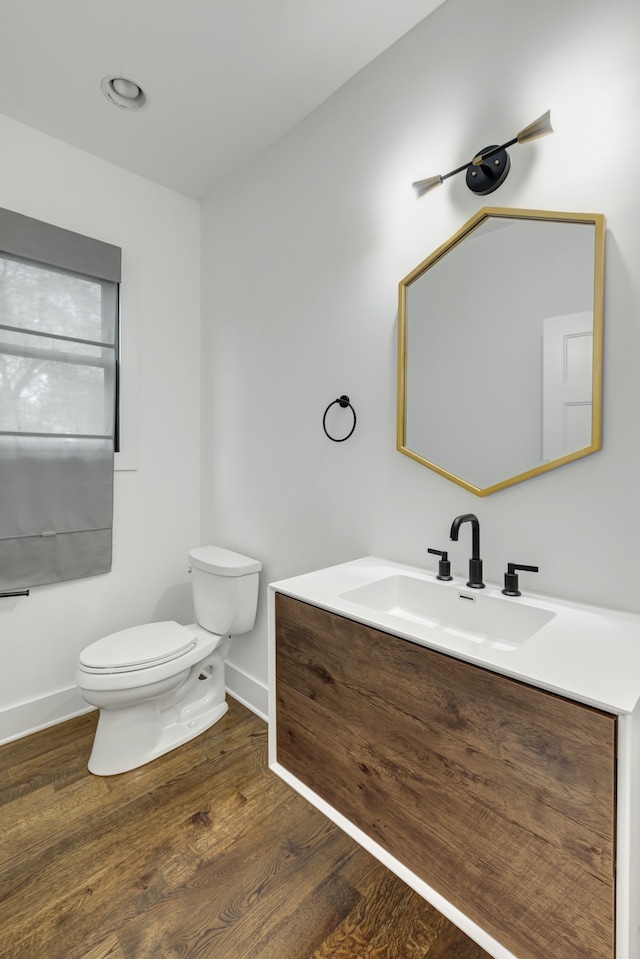 bathroom with wood-type flooring, toilet, and vanity