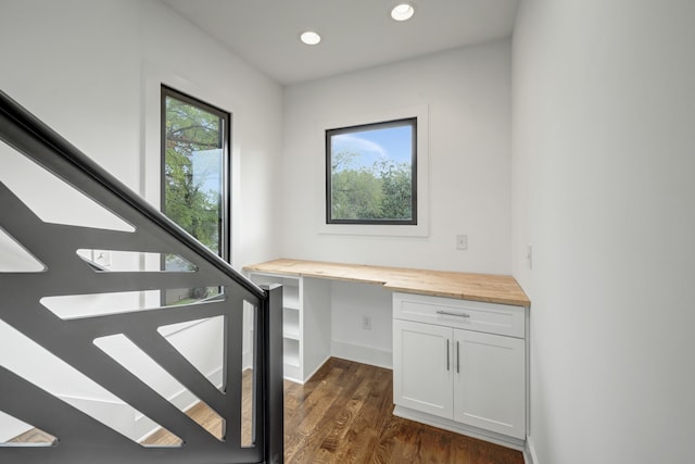 stairway featuring built in desk and wood-type flooring