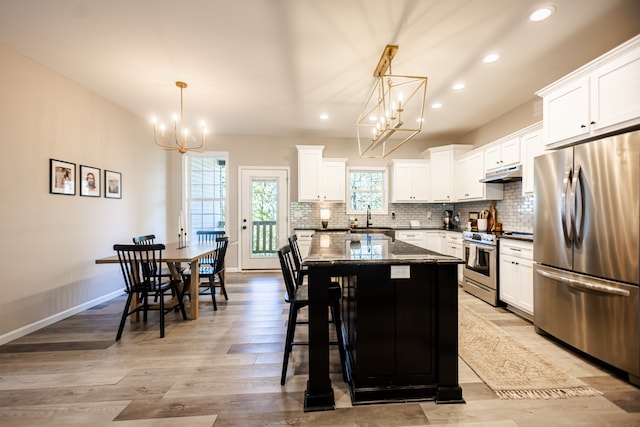 kitchen featuring a kitchen island, dark stone countertops, white cabinetry, and appliances with stainless steel finishes