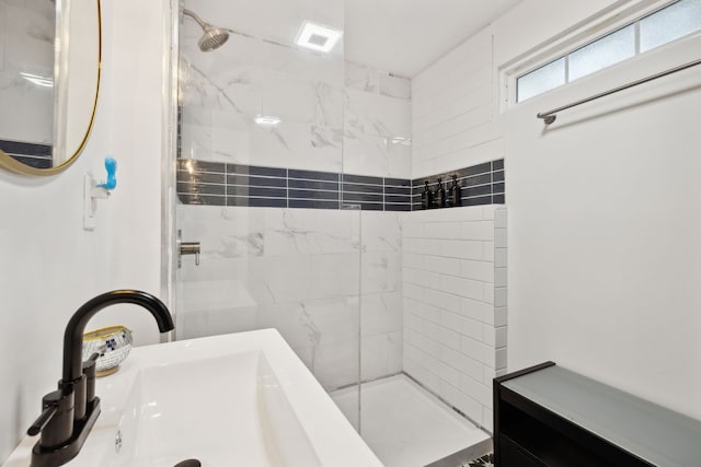 bathroom with tiled shower and sink