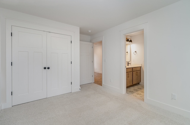 unfurnished bedroom with ensuite bathroom, light carpet, a closet, and sink