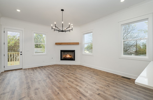 unfurnished living room with hardwood / wood-style floors, a chandelier, and crown molding