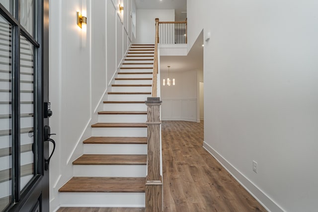 stairway featuring an inviting chandelier and wood-type flooring