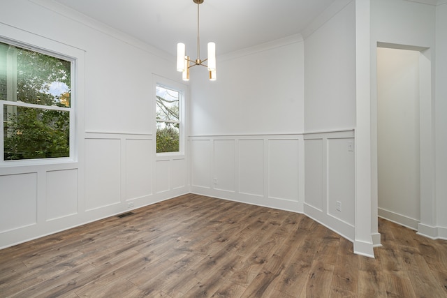 unfurnished dining area featuring ornamental molding, dark hardwood / wood-style floors, and an inviting chandelier