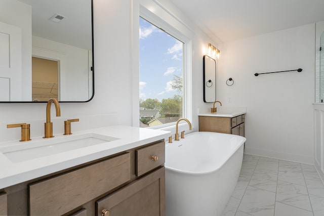 bathroom featuring a tub to relax in, vanity, and plenty of natural light