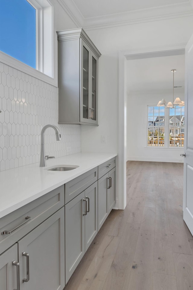 kitchen with ornamental molding, tasteful backsplash, a sink, and gray cabinetry