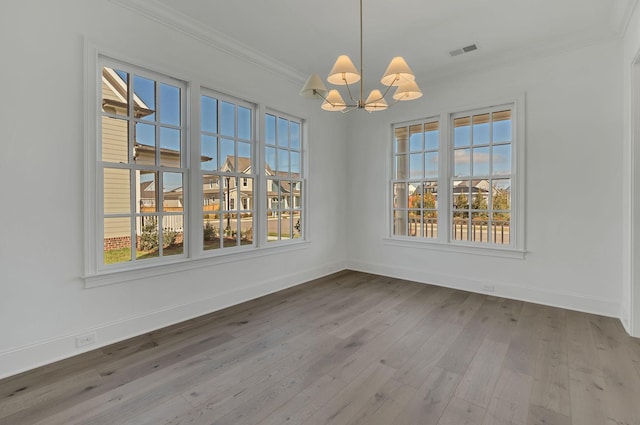 unfurnished dining area with a notable chandelier, wood finished floors, visible vents, baseboards, and crown molding