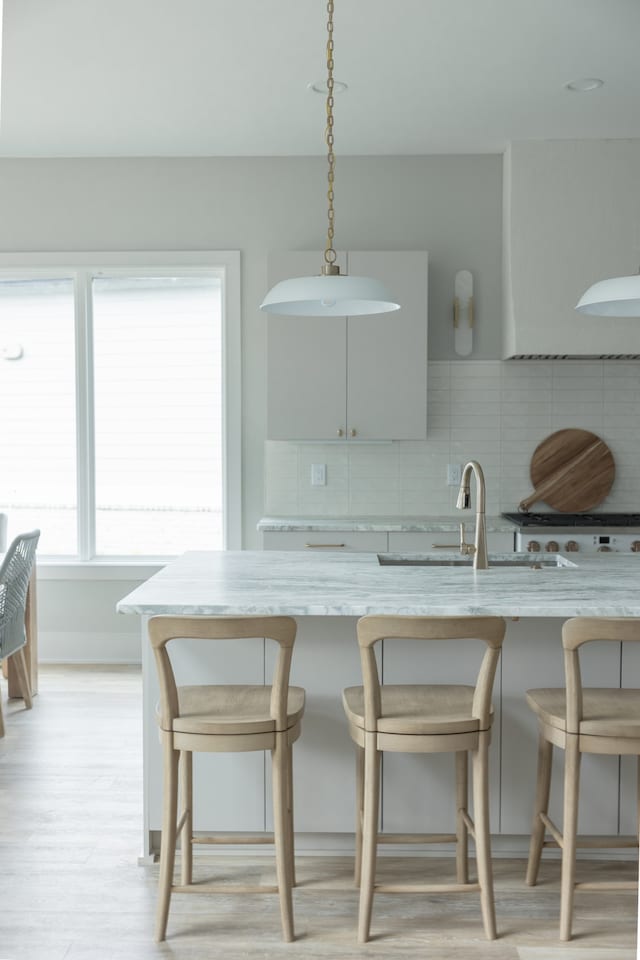 kitchen with decorative light fixtures, gray cabinets, backsplash, and a breakfast bar