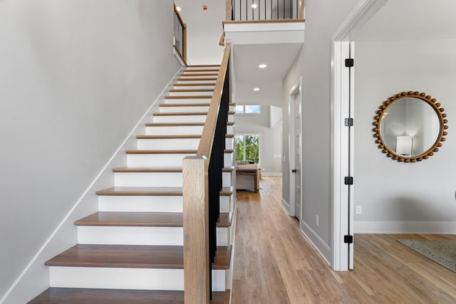 staircase with wood-type flooring and a high ceiling