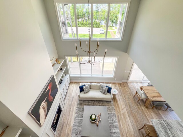 living room with light hardwood / wood-style flooring, a chandelier, and a high ceiling