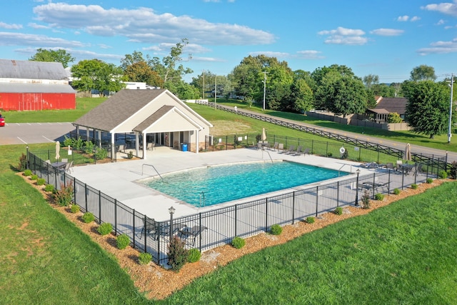 view of pool featuring a lawn, an outdoor structure, and a patio