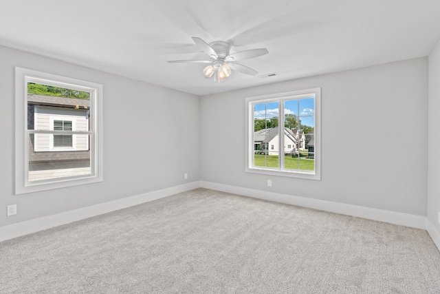 unfurnished room featuring ceiling fan, plenty of natural light, and light colored carpet