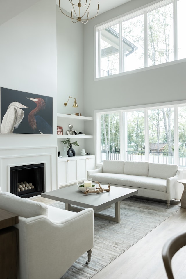 living room with plenty of natural light, a chandelier, a high ceiling, and wood-type flooring