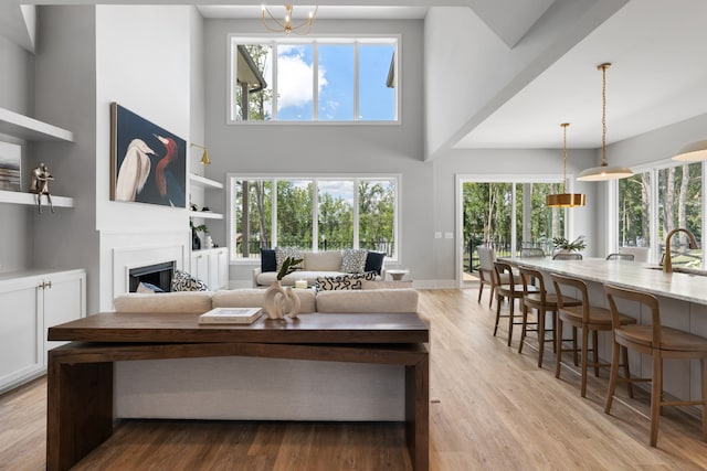 living room featuring sink, built in features, a towering ceiling, and light wood-type flooring