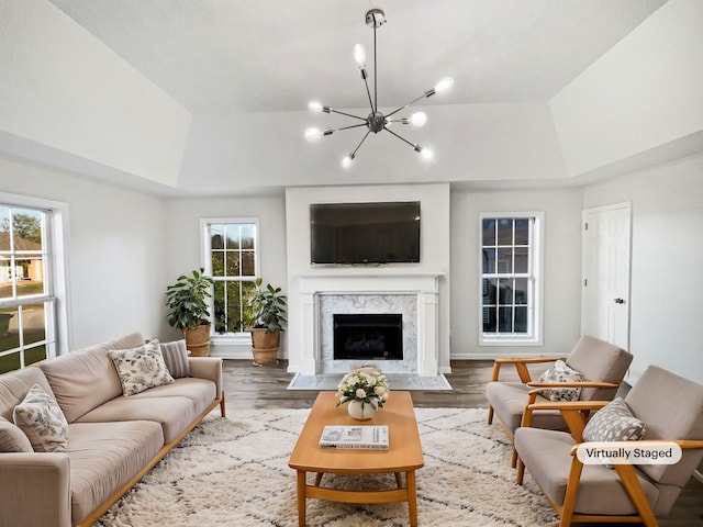 living room with a notable chandelier, hardwood / wood-style flooring, and a raised ceiling