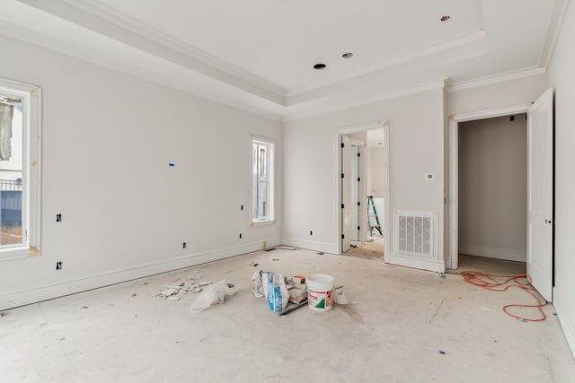 unfurnished bedroom featuring a tray ceiling, multiple windows, and ornamental molding