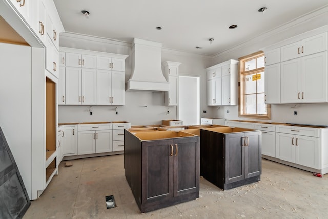 kitchen with premium range hood, crown molding, a center island, and white cabinets