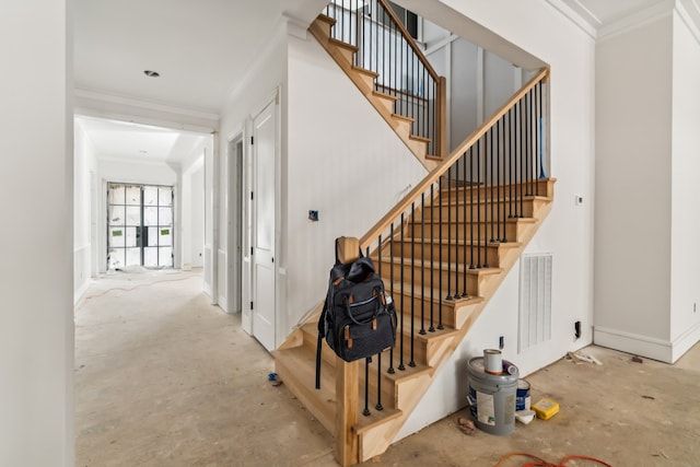 staircase with crown molding and concrete floors