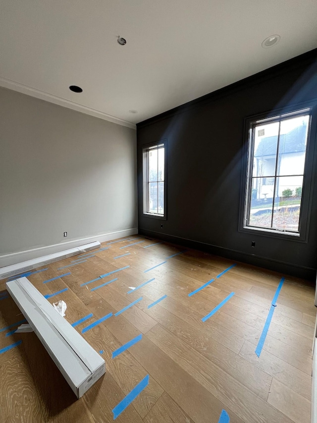 unfurnished room featuring light wood-type flooring, baseboards, crown molding, and recessed lighting