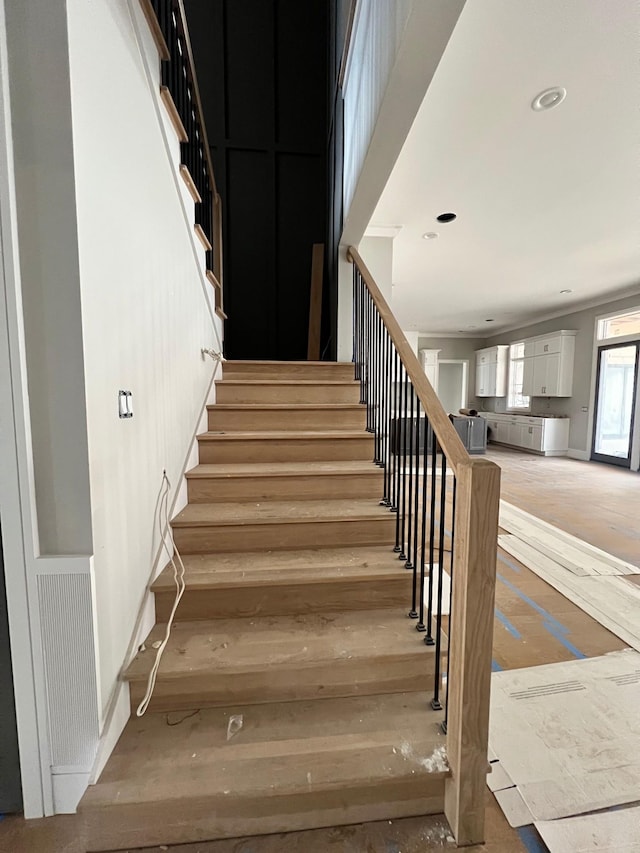 staircase with wood finished floors and recessed lighting