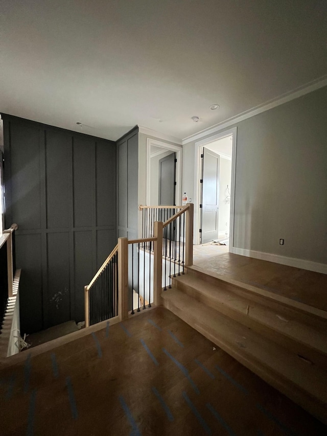 unfurnished room featuring baseboards, a decorative wall, crown molding, and wood finished floors