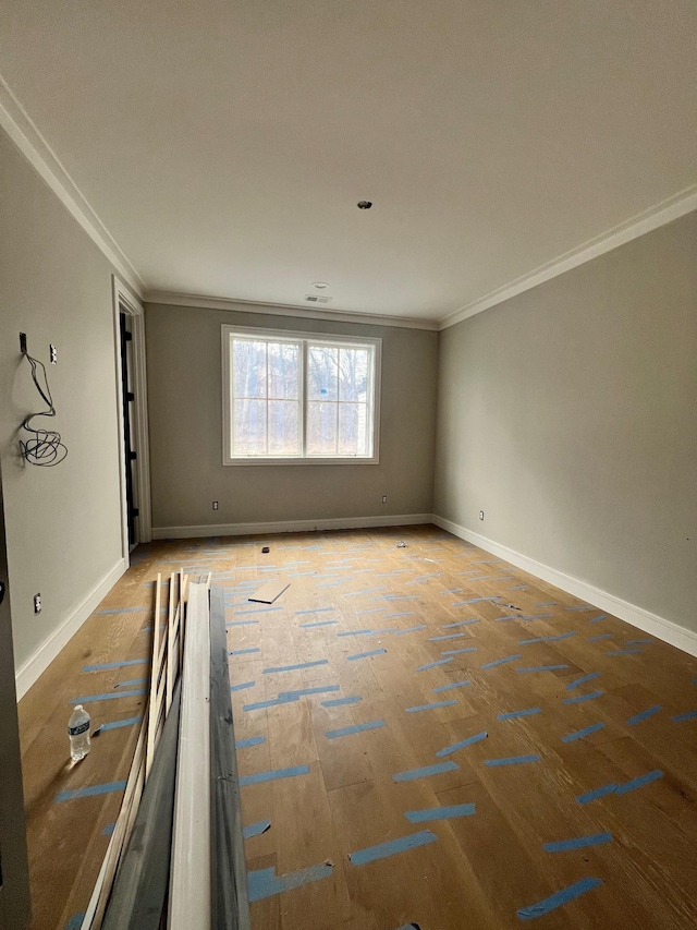 spare room featuring baseboards, crown molding, and wood finished floors