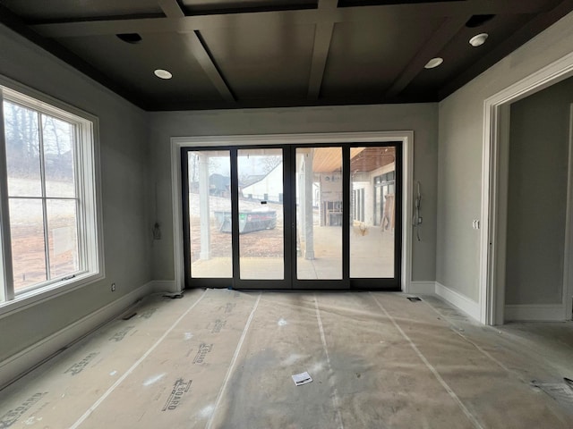 empty room with coffered ceiling, a wealth of natural light, and baseboards