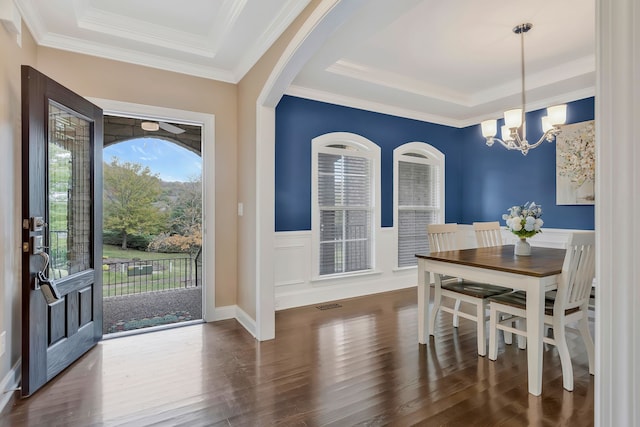 dining room with dark hardwood / wood-style flooring, a notable chandelier, ornamental molding, and a raised ceiling